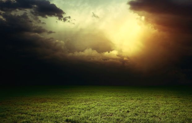 Storm clouds breaking over an open field of grass