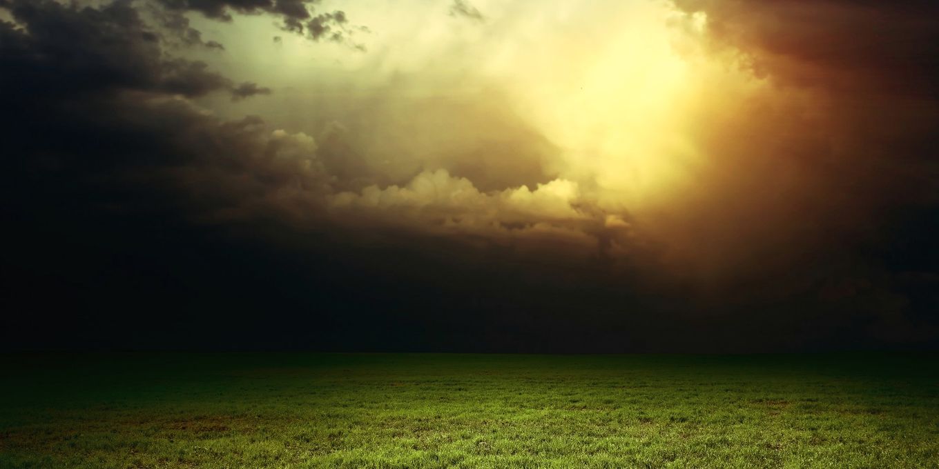 Storm clouds breaking over an open field of grass