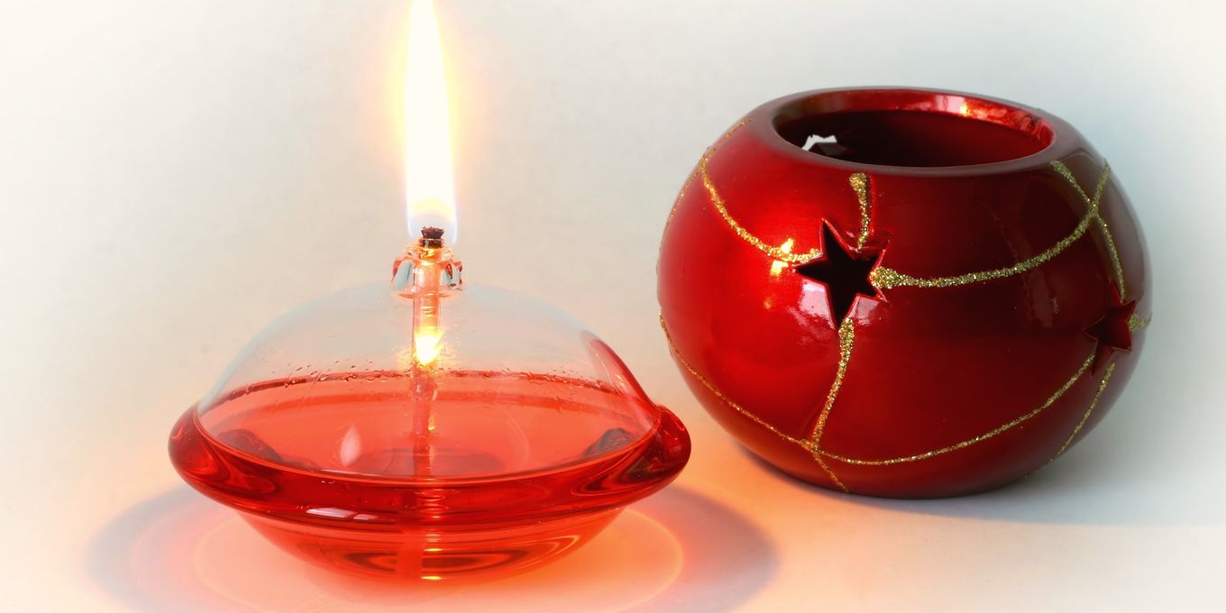 A small glass oil lamp burning beside a red candle holder