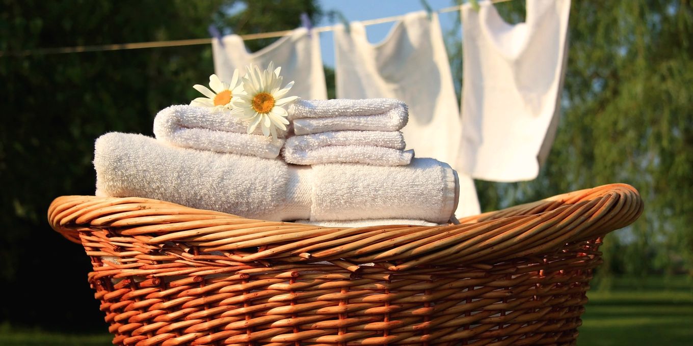 Folded towels in a wicker basket below washing on a line