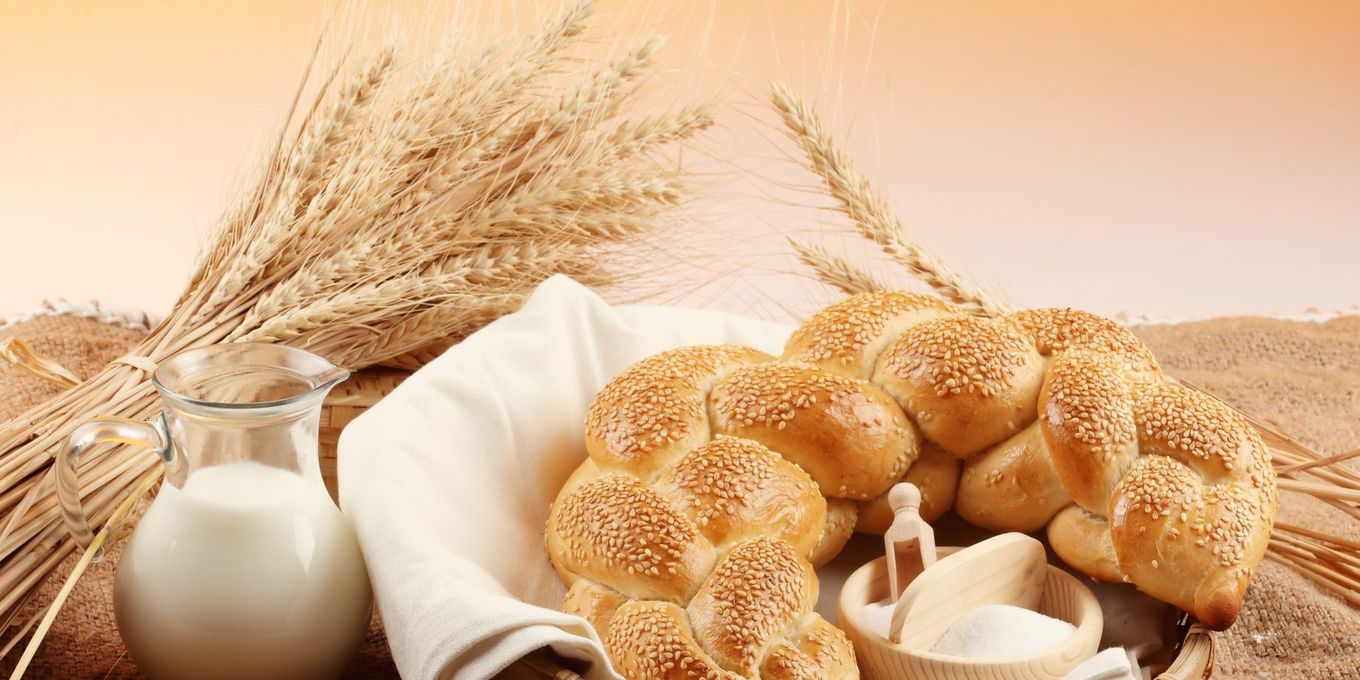 A jug of milk beside braided bread and wheat ears