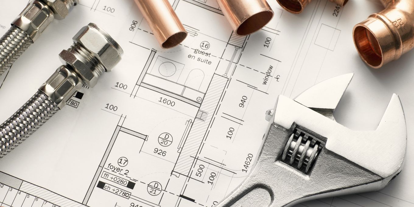 Copper pipe, brass fittings and an adjustable wrench on a plumbing plan