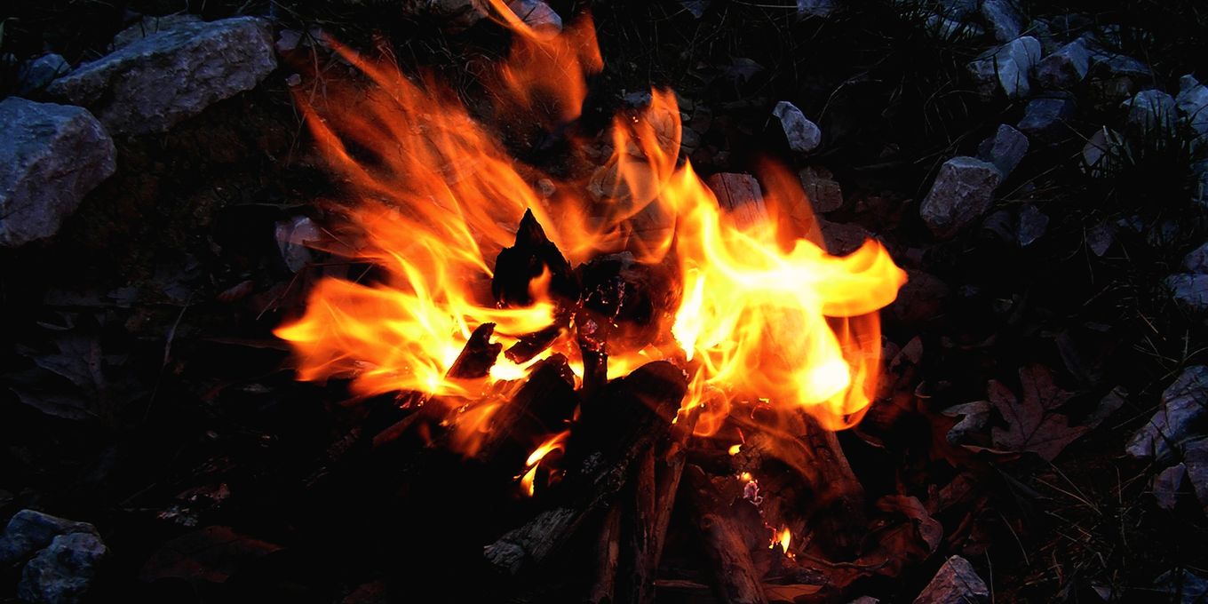 A small fire burning in a ring of stones at night